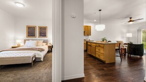Un'ampia camera da letto con un letto grande, comodini e un tavolino da notte. Accanto, una cucina con mobili in legno, un piano di lavoro e un'area pranzo.