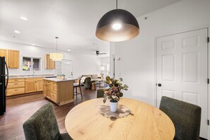 Eine moderne Küche mit Holzschränken, einem Esstisch mit Stühlen und einer Pendelleuchte.