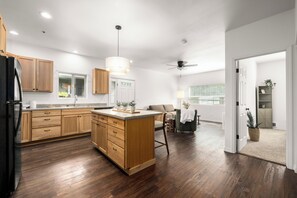 A modern kitchen with wooden cabinets, a central island, and a dining area with a sofa and chairs.