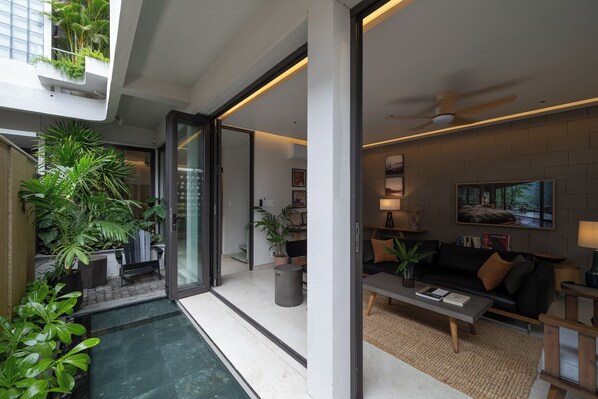 A modern living room with a sofa, coffee table, and potted plants.