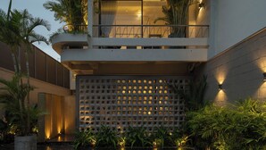 A modern building with a curved facade, a balcony with plants, and a water feature in the courtyard. - Holiday 3-Bedroom Delightful Villa @ Phan Thiet (Phan Thiết)