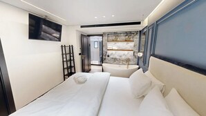 A modern bedroom with a large bed, a built-in bathtub, and a television mounted on the wall. - Luxury Garden Duplex Private Jacuzzi (Tel Aviv-Yafo)