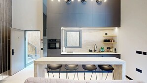 A modern kitchen with a central island, bar stools, and built-in appliances. - Luxury Garden Duplex Private Jacuzzi (Tel Aviv-Yafo)