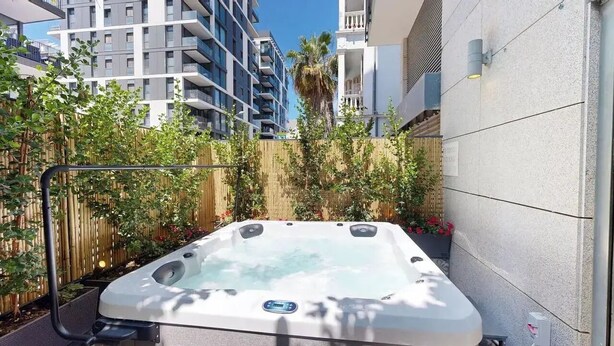 A hot tub in an outdoor setting with a bamboo fence and plants. - Luxury Garden Duplex Private Jacuzzi (Tel Aviv-Yafo)