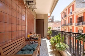 A balcony with a wooden bench, a small table with breakfast items, and potted plants. - Casetta Annina | Stylish 3BR Retreat in the Heart of Bari (Bari)