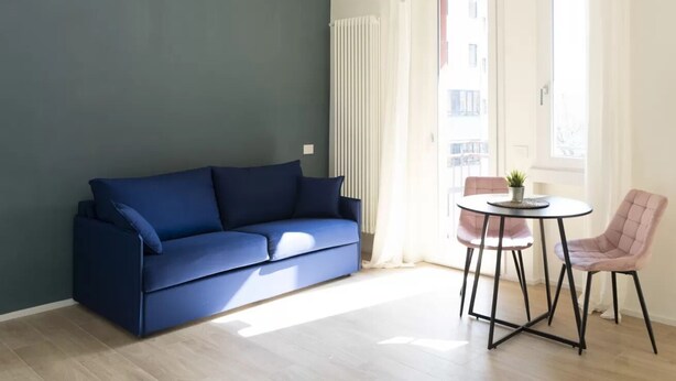 Ett rum med en blå soffa, ett litet runt bord och två stolar.