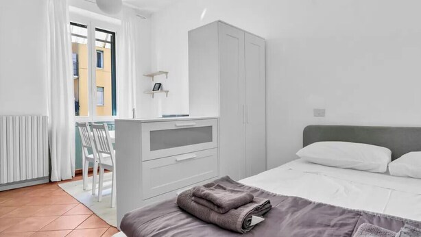 Een moderne slaapkamer met een bed, een kledingkast, een bureau en een stoel.