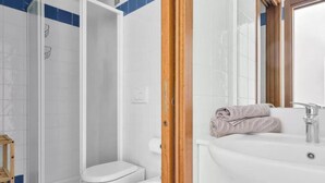Een badkamer met douche, toilet, wastafel en een handdoek op het aanrecht.