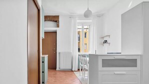 Een moderne keuken met witte kasten, een inbouwoven en een hanglamp.
