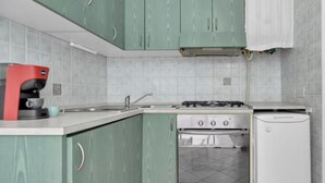 Een kleine keuken met een gasfornuis, oven en een kleine koelkast.