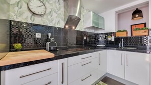 A modern kitchen with a black countertop, white cabinets, and a decorative backsplash. - LXR Townhouse, 2 Bedrooms, Near the Ocean (Las Lagunas de Mijas)