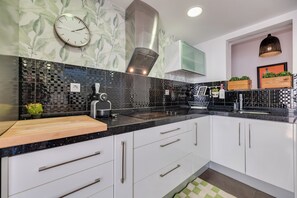 Uma cozinha moderna com bancada preta, armários brancos e painel decorativo.