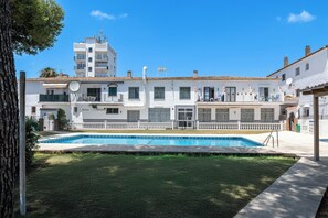 Um edifício residencial com piscina, varandas e um céu azul límpido.