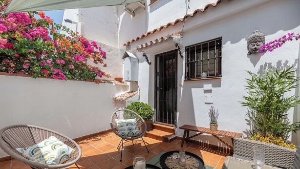 A patio with a chair, a small table, and a decorative Buddha statue. - LXR Townhouse, 2 Bedrooms, Near the Ocean (Las Lagunas de Mijas)