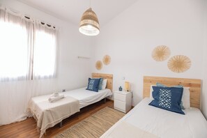 Une chambre d’hôtel avec deux lits, une table de chevet, une lampe et une fenêtre avec des rideaux.