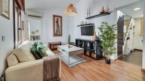 A modern living room with a sofa, coffee table, and a TV. There is a staircase leading to another level. - LXR Townhouse, 2 Bedrooms, Near the Ocean (Las Lagunas de Mijas)