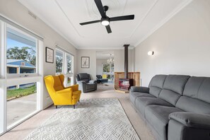A spacious living room with a grey sofa, a yellow armchair, and a ceiling fan.
