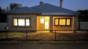 A single-story house with a metal roof, a chimney, and a fenced yard. - Brighton Belle — Mid-Century 2BR Home, Split Bath, Walk to Station & Main St (Stawell)