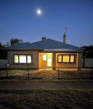 A single-story house with a metal roof, a chimney, and a fenced yard. - Brighton Belle — Mid-Century 2BR Home, Split Bath, Walk to Station & Main St (Stawell)