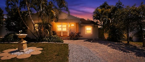 A house with a well-maintained lawn, a gravel pathway, and a decorative fountain.