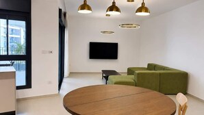 Una sala moderna con una mesa redonda de madera, sofá verde e iluminación colgante.