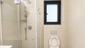 Un baño con ducha, inodoro y ventana.