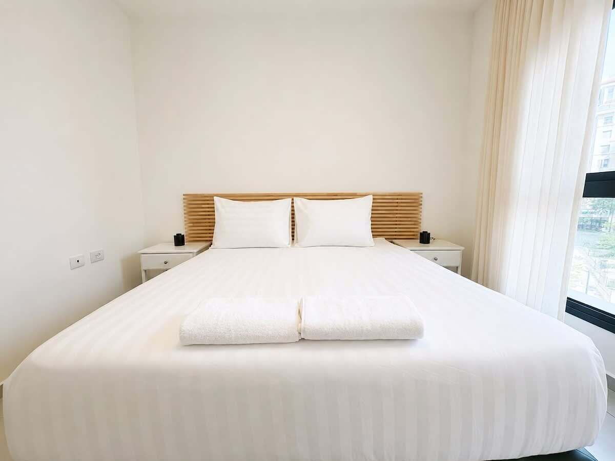 Ein Hotelzimmer mit einem großen Bett, zwei Nachttischen und einem Fenster mit Vorhängen.