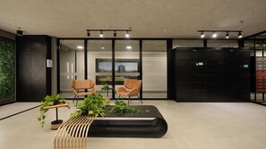 A modern office lobby with two leather chairs, a black reception desk, and a large window with a cityscape view.