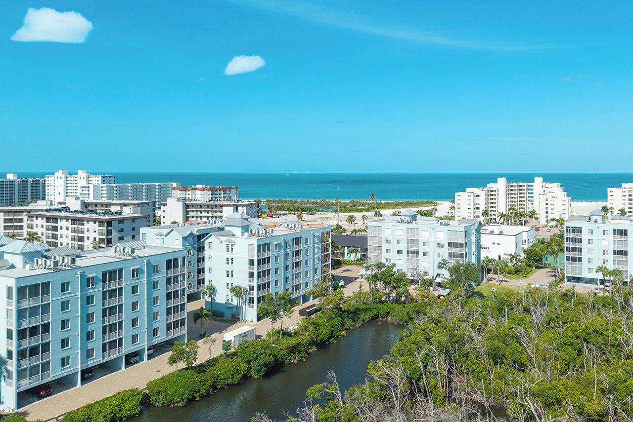A coastal hotel with multiple buildings, a river, and a clear view of the ocean.