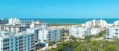 A coastal hotel with multiple buildings, a river, and a clear view of the ocean.