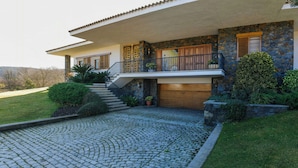 Ein zweistöckiges Haus mit einer Stein-Fassade, einer überdachten Veranda und einer Steintreppe, die zum Eingang führt.