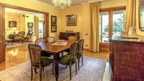 Ein Esszimmer mit Holztisch und -stühlen, einer Chandelüster und Blick durch das Fenster.