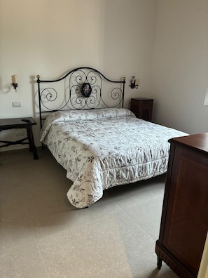 A bedroom with a bed, a nightstand, a dresser, and a wall-mounted lamp.