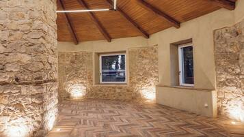 Una habitación con paredes de piedra, vigas de madera y un suelo con diseño en espiga.