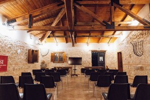 A conference room with rows of chairs, a television, and stone walls.
