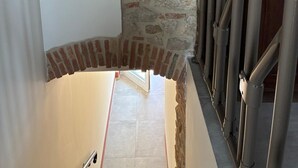 Una escalera con pared de piedra y barandilla de metal.