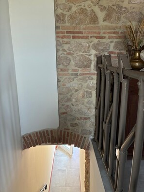 A staircase with a stone wall and a metal railing.