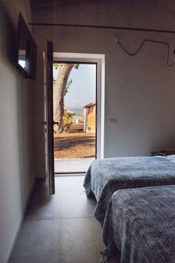A bedroom with a bed, a window, and a view of the outside.