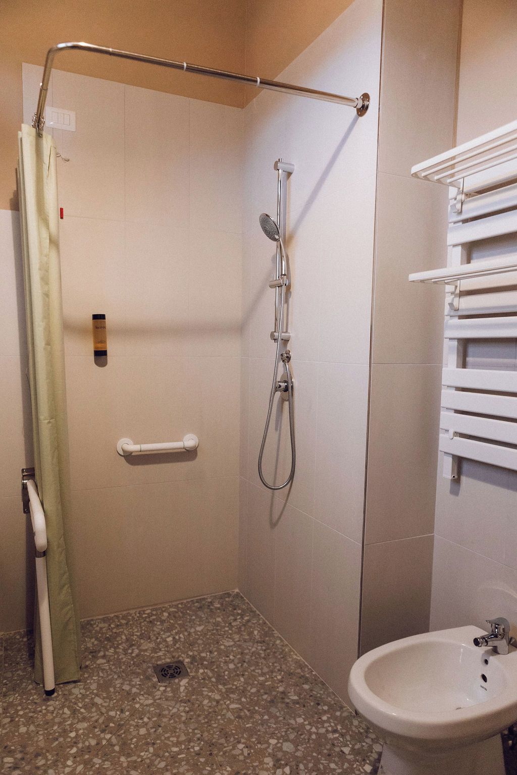A bathroom with a shower, a sink, and a towel rack.
