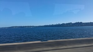 Une vue sur une étendue d’eau, avec une rive éloignée et une barrière en béton.