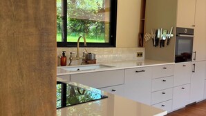 Eine moderne Küche mit großem Fenster, weißen Schränken und einem eingebauten Backofen.