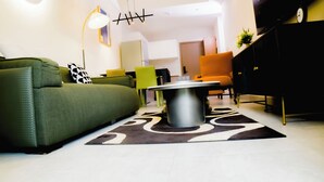 Una sala de estar moderna con un sofá verde, una mesa de centro redonda y una silla amarilla.
