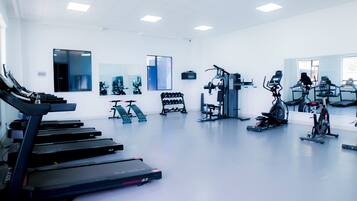 Een fitnessruimte met loopbanden, elliptische trainers en krachttoestellen.
