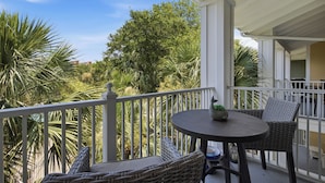 Ein Balkon mit Korbmöbeln, einem runden Tisch und einem Blumentopf.