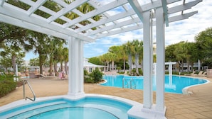 Ein Poolbereich mit Whirlpool, Liegestühlen und einer Pergola.