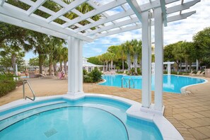 Ett poolområde med ett bubbelbad, solstolar och en pergola.