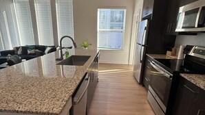 Una cocina moderna con encimeras de granito, electrodomésticos de acero inoxidable y una isla central.