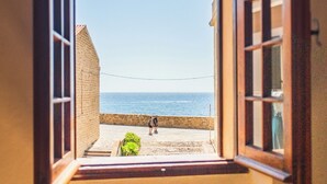 Ventana abierta con vista a una playa y un edificio.