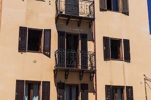 Ein mehrstöckiges Gebäude mit Balkonen, Fensterläden und einem zentralen Balkon mit aufwendiger Railing.