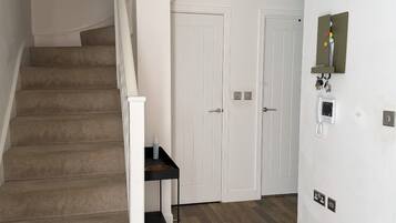 A staircase with carpeted steps, a small table with a bottle, and a wall-mounted phone.